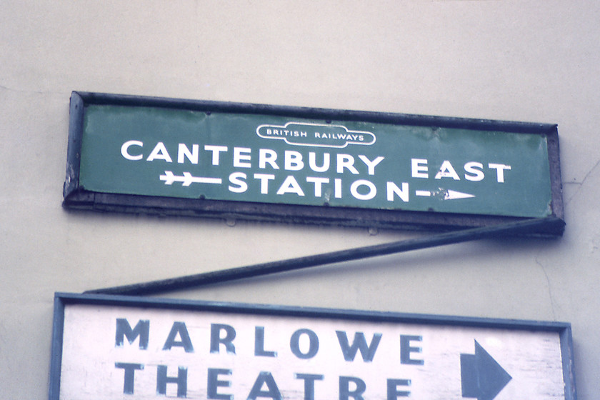 BR(S) enamel sign, Canterbury-03.01.81 
 While wandering around Canterbury on the morning of our journey home to Wiltshire I spotted these signs on a street corner. Unfortunately, my records do not have a note of the particular street that they were located. With one sign pointing to the well regarded Marlowe Theatre, the other is a sad-looking British Railways (Southern) enamel sign with a double arrow tail pointing towards Canterbury East station. Given that the Marlowe is nearer to Canterbury West station then I suspect that it was in this part of the town. Whilst the wooden frame is falling apart I hope that the sign survived to be rescued and saved. 
 Keywords: BR(S) enamel sign, Canterbury.