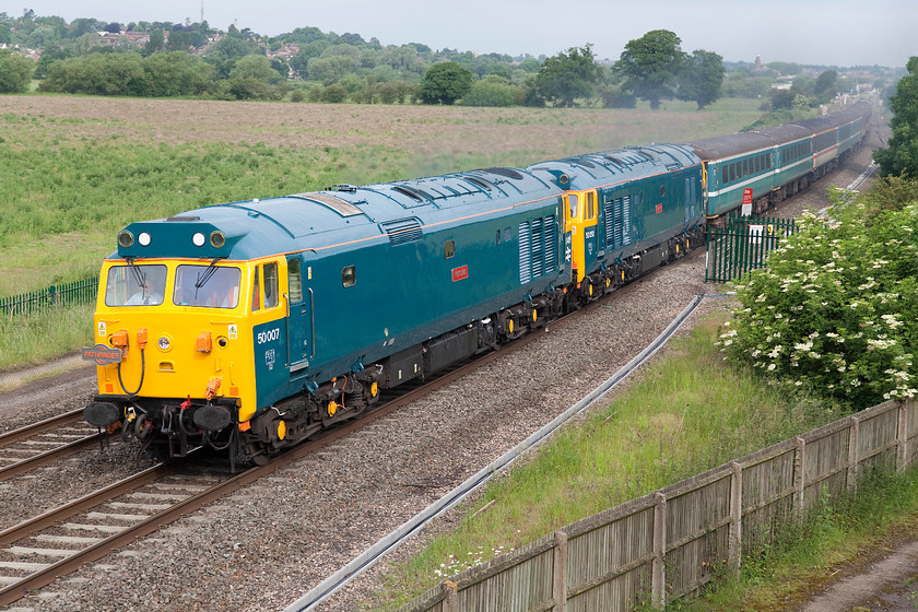 50007 & 50050, outward leg of The Purbeck & Bomo Explorer, 04.48 Derby-Swanage (1Z50), Warkworth SP476394 
 Running as 1Z50, the outward leg of The Purbeck and Bono railtour left Derby at the unearthly time of 04.48! It's now 07.30 and the train has just left Banbury. It is about to pass under the M40 motorway, the embankment of which I am utilising to get a high vantage point. The 'tour is being led by two beautifully restored Type 4s, 50007 'Hercules' and 50050 'Fearless' that, unfortunately, had just been powered back as they approached me as the train was pathed behind a stopper that was only just in front of it at King's Sutton. So, whilst the picture is reasonable, the DAT recording was somewhat compromised being dominated by the traffic above me on the M40! 
 Keywords: 50007 50050 The Purbeck & Bomo Explorer 04.48 Derby-Swanage 1Z50 Warkworth SP476394