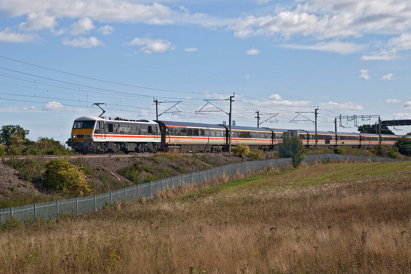 90002, 10.40 London Euston-Manchester Piccadilly (1Z94, 7E), Blisworth 
 90002 'Wolf of Badenoch' sweeps around a curve near to the Northamptonshire village of Blisworth leading the 10.40 Euston to Manchester Piccadilly 1Z94 LSL relief service. Unfortunately, I have not quite framed the image correctly managing to crop off the rear of the stock underestimating the length of the train when composing the photograph. Also, note that following the clear blue skies of earlier that the cloud is beginning to build. 
 Keywords: 90002, 10.40 London Euston-Manchester Piccadilly 1Z94 Blisworth Intercity swallow Wolf of Badenoch