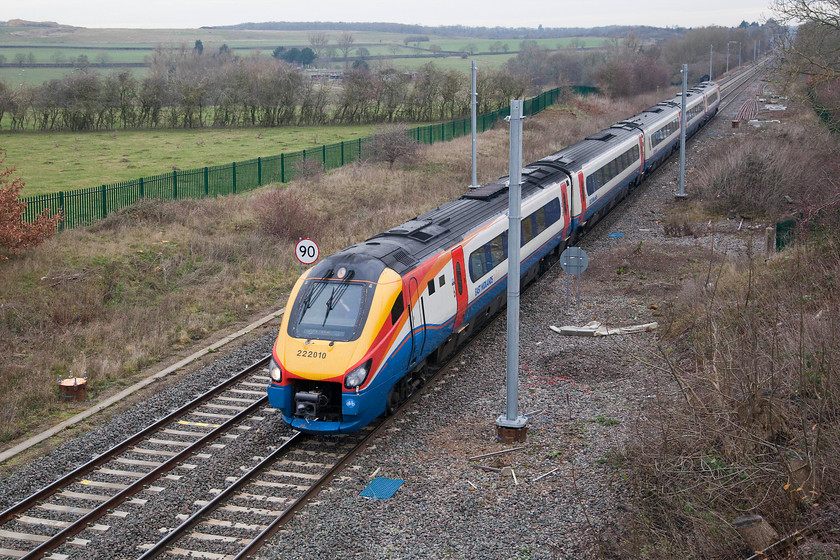 222010, EM 10.41 Corby-LondonSt. Pancras (1P09, 4L), Glendon Iron-Coys bridge SP854823 
 When I first visited this location in 1980 there were some sidings to the right where open cast iron ore was transferred from a narrow-gauge network to wagons for onwards movement. In the distance, where the palisade fence dips down out of view, was Glendon Sidings signal box complete with a number of semaphores, see.... https://www.ontheupfast.com/p/21936chg/29663553404/x16-glendon-sidings-signal-box-mid The track was still doubled but soon it was to be singled and then, in the last two years doubled again! 222010 forms the 10.41 Corby to London St. Pancras that is about to rejoin the route of the Midland Mainline and stop at Kettering. 
 Keywords: 222010 10.41 Corby-LondonSt. Pancras 1P09 Glendon Iron-Coys bridge SP854823