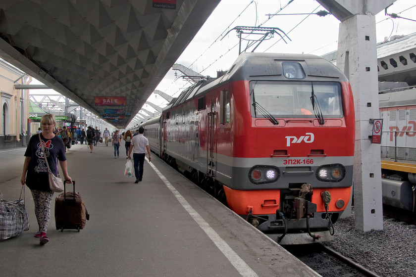 EP2K-166, stabled, St. Petersburg Moskovsky station 
 One of Russian Railway's relatively new EP2K electric locomotives sits at the stops of St. Petersburg Moskovsky station having arrived with an unidentified service. This example, EP2K-166, was built at the huge Kolomna factory some 100km south-east of Moscow. With their one-piece windscreens and slab front they bear a resemblance to our own class 67. 
 Keywords: EP2K-166 St Petersburg Moskovsky station