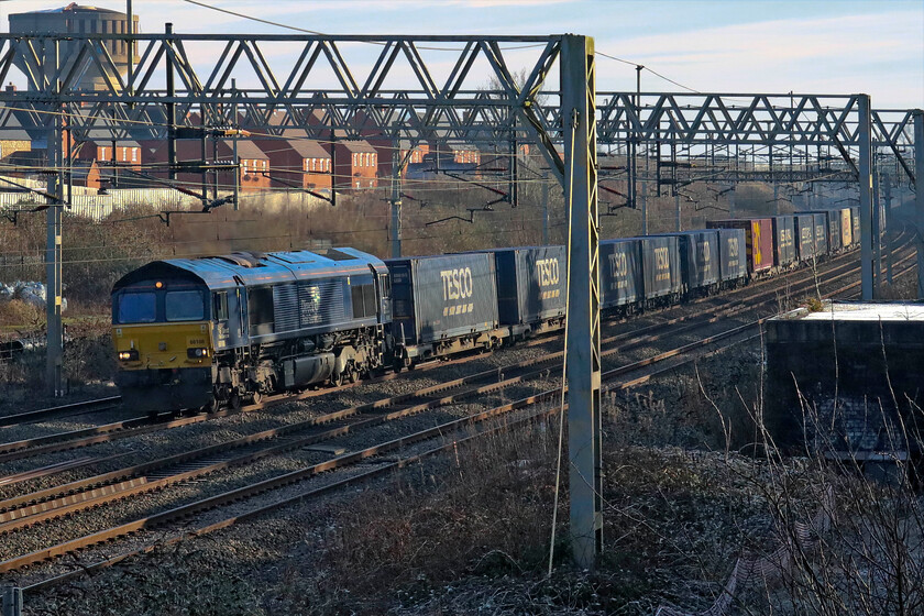 66108, 10.02 Tilbury FLT-DIRFT (4M07, 2E), site of Roade station 
 I last saw DRS' 66108 back in November hauling the same train, the 4M07 10.02 Tilbury to Daventry (DIRFT) Tesco Express but slightly further north than this in the cutting at Roade. Today, it is seen approaching the village from the south in the mid-afternoon winter's sunshine. This does not belie the fact that it was a very cold afternoon with the temperature still below freezing; notice the frost still laying in the foreground. 
 Keywords: 66108 10.02 Tilbury FLT-DIRFT 4M07 site of Roade station Tesco Express DRS Direct Rail Services