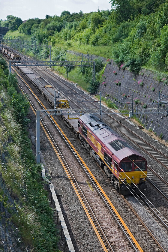 66024, down infrastructure working, Roade cutting 
 660024 leads a down unidentified infrastructure train through Roade cutting that I presume is heading for Bescot in Birmingham. 66007 is just visible on the rear of the train that originated in the north London area. 
 Keywords: 66024 down infrastructure working Roade cutting EWS