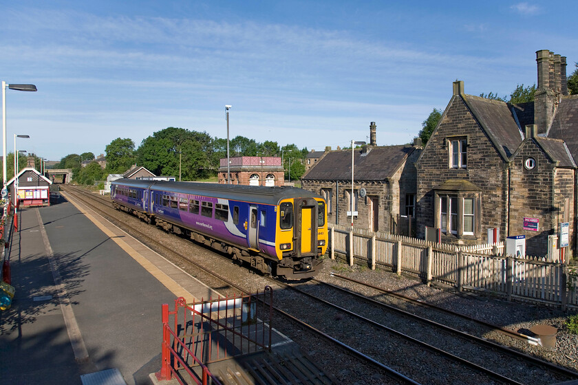 156443, NT 07.45 Dumfries-Newcastle (2N12), Haltwhistle station 
 Standing on Haltwhistle stations cast iron footbridge looking west gives a commanding view of the station and its associated buildings. 156443 leaves the station working the 07.45 Dumfries to Newcastle service. To the right is the former station building and in the background is the preserved and restored former water tower. 
 Keywords: 156443 07.45 Dumfries-Newcastle 2N12 Haltwhistle station Northern Trains