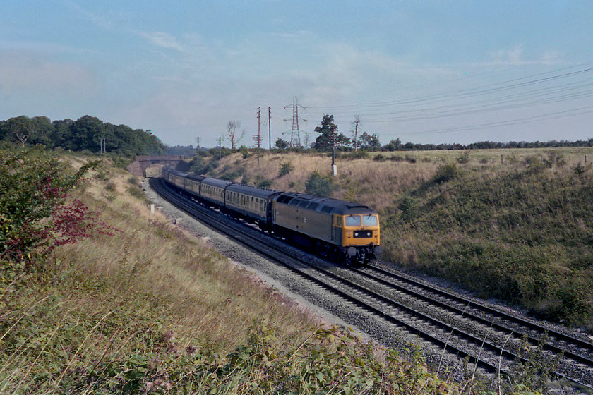 47486, unidentified down working, Clink Road Junction 
 47486 approaches Clink Road Junction at Frome with a down working from Paddington. As it is composed of Mk. I stock, it could well be a relief or perhaps the 1B48 09.48 Paddington to Newquay. The bridge in the background is still extant carrying a footpath over the railway. To the right of the line the field now has a huge cutting cut into it that contains the A361 Frome bypass. Quite why I took this picture from this angle with the sun on the wrong side is beyond me but I was a young photographer back in 1978! 
 Keywords: 47486 down working Clink Road Junction