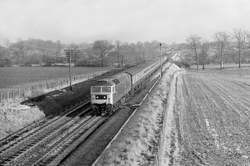 47440, unidentified down working, Woodborough 
 As the afternoon shadows lengthen, 47440 brings an unidentified down working past Woodborough in Wiltshire. The picture is taken from a road bridge just east of the signal box that also was the location of the old station that closed in April 1966. Just beyond the home signal about level with the rear of the train is a new colour light that would be commissioned the following weekend. The feather for the loop that started just the other side of the bridge that I'm standing on can be seen. 
 Keywords: 47440 down working Woodborough