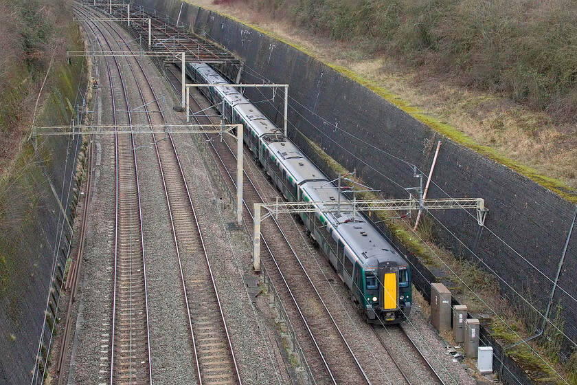 350119, 12.06 Birmingham New Street-London Euston (1Y18, RT), Roade cutting 
 London Northwestern Desiro 350119 leads another unit out of the 'birdcage' and into the depths of Roade cutting working the 12.06 Birmingham New Street to Euston service. The photograph is taken from the lofty heights of Bridge 210 'Accommodation' bridge the tallest of all the structures that cross the cutting and the one that carries the least traffic having a very overgrown footpath and farm access track atop. 
 Keywords: 350119 12.06 Birmingham New Street-London Euston 1Y18 Roade cutting London Northwestern Desiro