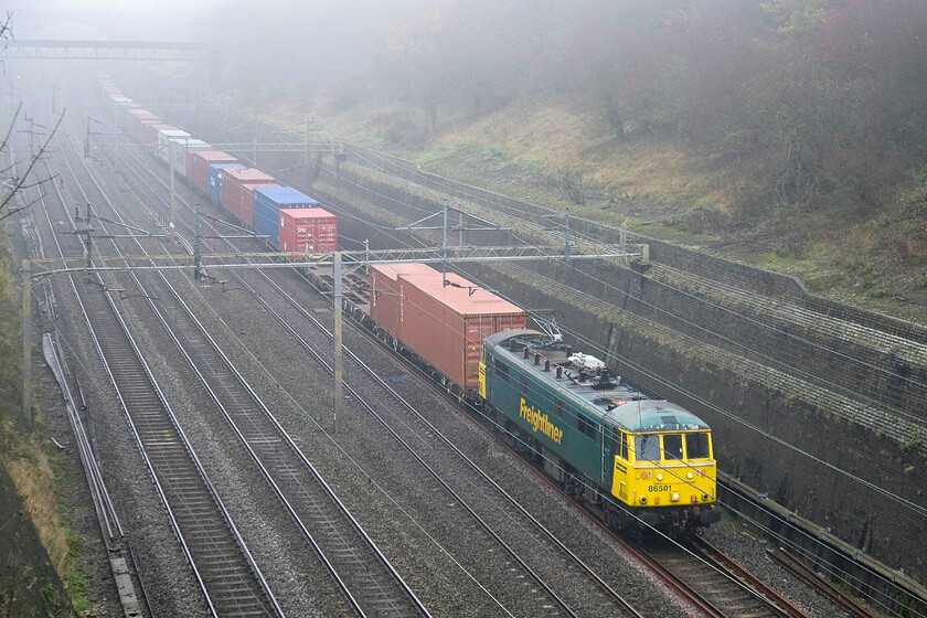 86501, 08.21 Crewe Basford Hall-Felixstowe North (4M87), Roade cutting 
 86501 emerges from the fog deep in Roade cutting leading Freightliner's 08.21 Crewe Basford Hall to Felixstowe train. I could hear the AL6 working well heading the 4M87 well before it came into view! 
 Keywords: 86501 08.21 Crewe Basford Hall-Felixstowe North 4M87 Roade cutting AL6