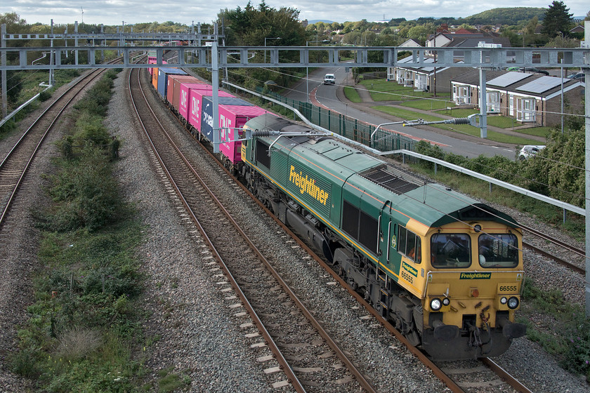 66555, 13.29 Wentlog-Southampton MCT (4O57), Undy 
 66555 leads the 13.29 Wentlog to Southampton Freightliner past Undy just west of Severn Tunnel Junction. Unfortunately, the installation of the electrification paraphernalia has completely ruined the view from this once popular location on one of the village's footbridges. Also, the newly constructed footbridge itself has the usual anti-suicide parapets, all very laudable but ruinous from a photographic point of view. This picture was taken using the camera with the fold-out screen out and the camera held up over the parapet in the hope of capturing a decent image. More than by chance, if I'm absolutely honest, this technique worked on this occasion. 
 Keywords: 66555 13.29 Wentlog-Southampton MCT 4O57 Undy