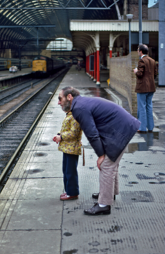 Watching the trains, London King's Cross station 
 An age-old activity at King's Cross; watching the trains! Possibly a grandfather discusses trains with his granddaughter whilst an enthusiast stands by with his camera in his hand. In the background 55004 'Queen's Own Highlander' is visible at the head of the 16.05 semi-fast to York. I have in my notes that there were numerous official notices around King's Cross station advising that trainspotters were banned from the platforms due to an injury sustained by one at an outer suburban station; can anybody shed any information on this? I can report that none of those seen in this image including myself had a visit from platform staff! 
 Keywords: Watching the trains London King's Cross station Queen's Own Highlander 55004 Deltic