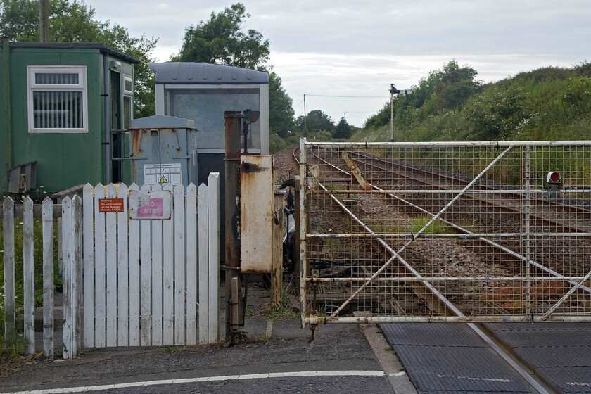 Kirkstanton MCG 
 The second MCG (Manually Controlled Gate) crossing within less than a mile is seen on the A5093 road at Kirstanton. The signalman has the luxury of a protected cabin here; something that does not exist at the nearby Limestone Hall crossing. The home signal is controlled within the absolute block between Silecroft and Millom. Both the crossings also have combined home and distant bracket signals, very few of these are now left in operation. I have crossed this level crossing a number of times including during my first visit to the area in 1985 but did not bother to stop and photograph the mechanicals! 
 Keywords: Kirkstanton MCG