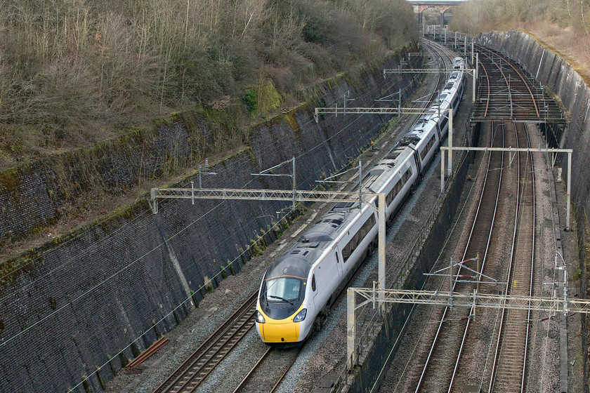 390043, VT 12.55 Manchester Piccadilly-London Euston (1A31, RT), Roade cutting 
 390043 sweeps around the curve off the Weedon loop line to rejoin the Northampton lines at the very northern end of Roade cutting. The 12.55 Manchester to Euston service will then run along the quadruple section of track all the way to the capital. The Northampton lines dive away to the right passing underneath what is colloquially referred to as 'The Birdcage' - constructed in order to support the cutting walls following their partial collapse in 1890. 
 Keywords: 390043 12.55 Manchester Piccadilly-London Euston 1A31 Roade cutting Avanti West Coast Pendolino