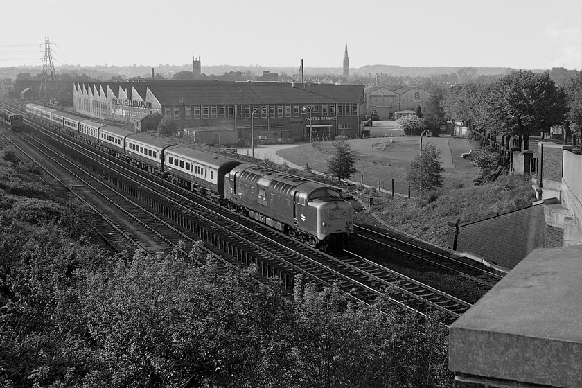 55002, 1510 Edinburgh Waverley-London Kings Cross (1E13), South Parade bridge, Grantham 
 After our evening meal at the Youth Hostel in Grantham we went out again. Simon went to the station and I went up to South Parade bridge to the south of the town. Here, 55002 'The King's Own Yorkshire Light Infantry' climbs away from Grantham as it begins the assault of Stoke Bank with the 1E13 15.10 Edinburgh to King's Cross. Behind the train is the parts and service department of Aveling Barfords former factory that made all sorts of heavy plant equipment whilst the town of Grantham basks behind in the evening sunshine. 
 Keywords: 55002 1510 Edinburgh Waverley-London Kings Cross 1E13 South Parade bridge Grantham