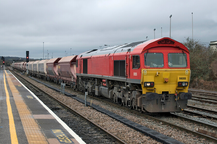 59205, 11.23 Merehead-Wootton Bassett (7B12, 15L), Westbury station 
 Composed of a mixture of HOA aggregates hopper wagons and former National Power converted JHA wagons the 7B12 11.23 Merehead to Wootton Bassett gets away from Westbury led by 59205. Whilst this Class 59 still wears its DB Schenker livery all branding has been removed as it has been operated by Freightliner since 2019 and they seem to be in no rush to repaint these hard-working diesels dating from October 1996. 
 Keywords: 59205 11.23 Merehead-Wootton Bassett 7B12 Westbury station