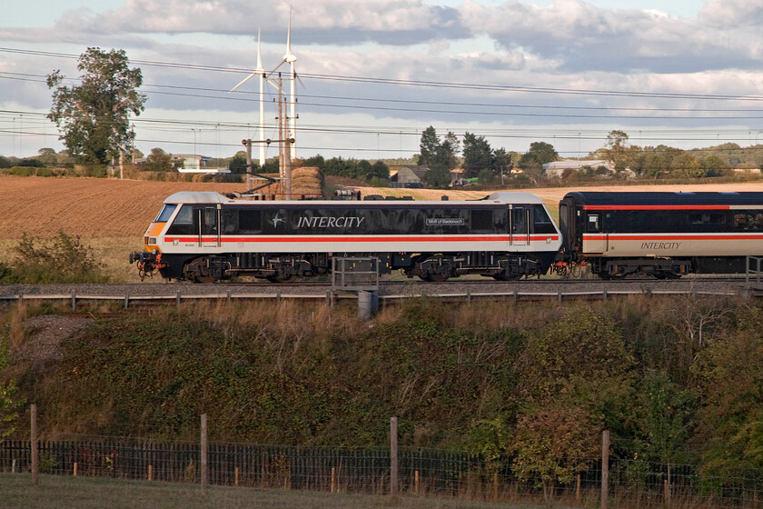 90002, 16.21 Manchester Piccadilly-London Euston (1Z96, 2E), Roade hill 
 90002 'Wolf of Badenoch' powers the rear of the 1Z96 16.21 Manchester Piccadilly to Euston relief service past Roade hill in Northamptonshire. The sun had just managed to hide behind a stubborn cloud with the fields, Salcey Forest and the M1 windfarm all bathed in sunshine but the subject in the shade; oh. the perils of railway photography! 
 Keywords: 90002 16.21 Manchester Piccadilly-London Euston 1Z96 Roade hill Wolf of Badenoch LSL Locomotive Services LTD