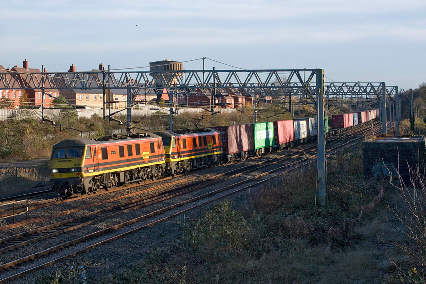 90006 & 90013, 09.12 Felixstowe North-Trafford Park (4M63, RT), site of Roade station 
 90006 'Roger Ford' and 90013 lead the 4M63 09.12 Felixstowe to Trafford Park Freightliner service past Roade. This spot has become a popular one for local enthusiasts with its wide open and well-lit views of northbound services since the clearance of undergrowth. However, I notice that rather worryingly that it is growing back and will once again be causing problems unless Network Rail attends again with their strimmers in-hand! 
 Keywords: 90006 90013 09.12 Felixstowe North-Trafford Park 4M63 site of Roade station Freightliner Roger Ford