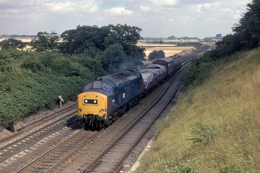 37173, up freight, Eaton Wood SK723774 
 37173 dashes south in between express passenger workings on the ECML at Eaton Wood with a very short up freight. The loss of these grossly uneconomical short mixed freights is something enthusiasts mourn but one that the accountants would applaud! This location is just south of Retford, indeed, the southern edge of the town can be seen in the top left of the photograph. This class 37 was renumbered 37801 in 1985 and eventually moved to the continent as an infrastructure locomotive and was cut up in Spain by the Celsa Group. 
 Keywords: 37173 up freight Eaton Wood SK723774