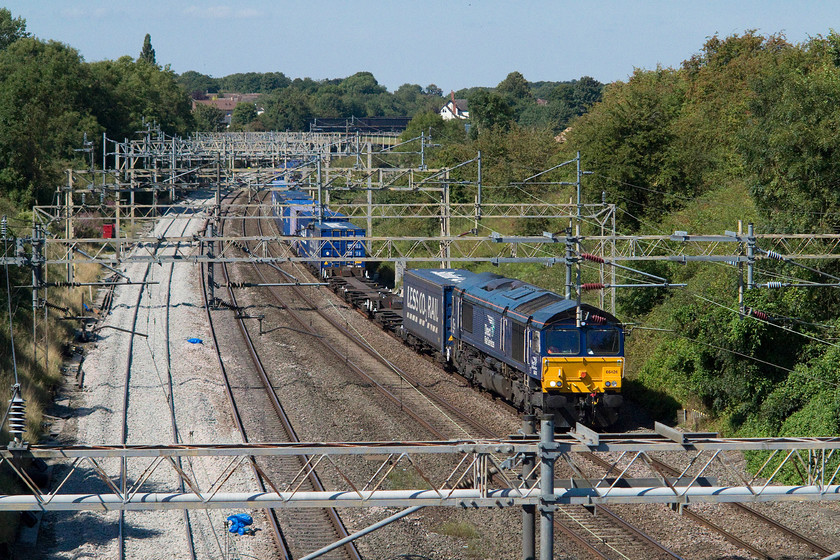 66426 12.37 Daventry-Purfleet (4L48), passing the TSR, Ashton Road bridge 
 66426 leads the 12.37 Daventry to Purfleet 4L48 Freightliner that is about to pass under Ashton Road bridge with the village of Roade in the background. The white building seen above the trees is the former Station Master's house that stands above the site of the old station that closed on 07.09.64. 
 Keywords: 66426 12.37 Daventry-Purfleet 4L48 passing the TSR, Ashton Road bridge