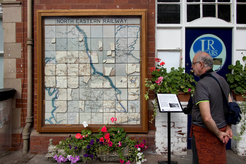 Andy & NER restored tiled map, Bridlington station 
 One of the original NER glazed tiled maps that was once positioned on Bridlington's platform one is in the process of being recreated inside the concourse of the station. There were thought to be twenty-five of these maps, manufactured by Craven, Dunnill & Co of Ironbridge in Shropshire. This example was destroyed in an act of 'developer vandalism' in 1987 when Bridlington station was being refurbished. After being left in rubbish bags stored at Hull Paragon station and forgotten about for many years until they were rescued and subsequently acquired by the North Eastern Railway Association. The map has now been reinstated with a local craftsman having to manufacture the missing pieces. The original remaining pieces are those attached in relief on the map. Andy inspects the work undertaken by NER Association so far. 
 Keywords: Andy NER restored tiled map Bridlington station