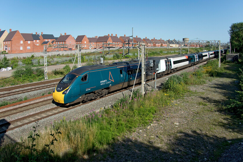 390040, VT 16.41 London Euston-Birmingham New Street (6G34, 1L), site of Roade station 
 A more unusual photograph of 390040 working the 6G34 16.41 Euston to Birmingham New Street Avanti service as it passes Roade. It is taken with the camera's lens at its widest angle displaying a lot more of the scene that was once full of sidings and with the large Pianoforte factory occupying the site that is now a large housing estate. With the lens at this extreme setting, some work was needed in Photoshop to straighten things up with all sorts of converging horizontal and vertical planes but it makes for a change from a more conventional setting. 
 Keywords: 390040 16.41 London Euston-Birmingham New Street 6G34 site of Roade station Avanti West Coast Pendolino