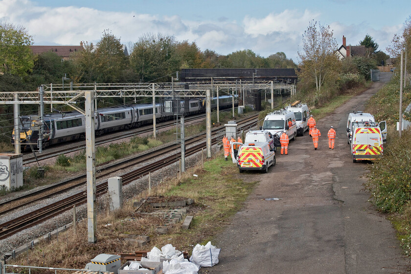 221101 & 221106, stopped & work crew, site of Roade station 
 Several vans had gathered at Roade on the site of the old station preparing themselves to assess and then prepare to clear the lines from fallen tree debris. Unfortunately, at this stage, I am not at all sure that they realised quite what they were up against in terms of the damage done. For example one of the workers rather optimistically took a step ladder and a single registration arm with him not realising that he would need another four at this location alone! I find it utterly frustrating watching NR rail staff, the fabled 'orange army'. They are so slow in their work spending all their time on their mobile 'phones rather than actually getting on with it! Now, where did I leave my tin hat?! 
 Keywords: 221101 221106 stopped work crew site of Roade station Avanti West Coast Voyager