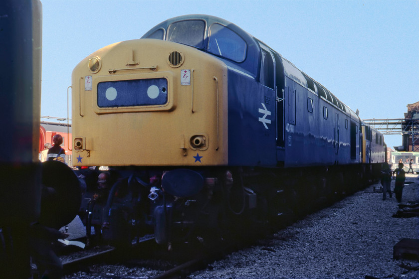 40181 & 82008, awaiting attention, Crewe Works 
 40181 sits, unfortunately, in the shade at Crewe Works. This locomotive had spent a lot of time on the works having been there, but for a short break from October 1978 until January 1979 receiving wheelset and classified repairs. Unfortunately, less than two months after being released it was back again after sustaining accident damage! These repairs were completed and it left the works a month after this photograph was taken. I wonder if the glass headcode panel was replaced before it left as it seems to have a very neat hole punched in it? Behind the class 40 is AC electric 82008. This still had another three years in service before withdrawal. It is still with us today preserved at Barrow Hill painted into the InterCity Executive livery and undergoing a protracted mechanical restoration. 
 Keywords: 40181 82008 awaiting attention Crewe Works