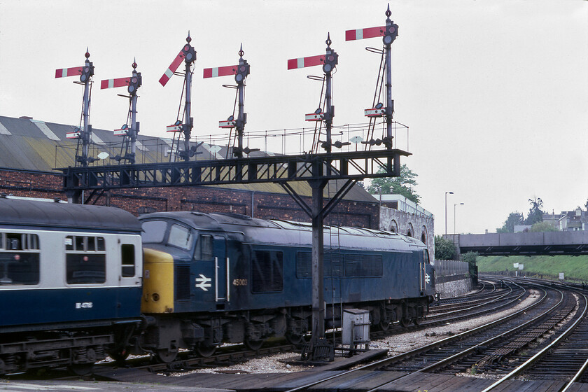 45003, 08.38 Manchester Picadilly-Paignton (1V32), Newton Abbot station 
 45003 leads the 1V32 08.38 Manchester to Paignton service away from Newton Abbot just a few miles from its desitnation. The locomotive is passing under the superb six doll gantry that was controlled by the West signal box just off to the right. Notice the attached set of calling on arms at the base of the dolls permitting drivers to pass the main arms at danger at extreme caution as far as the next stop signal. 
 Keywords: 45003 08.38 Manchester Picadilly-Paignton 1V32 Newton Abbot station