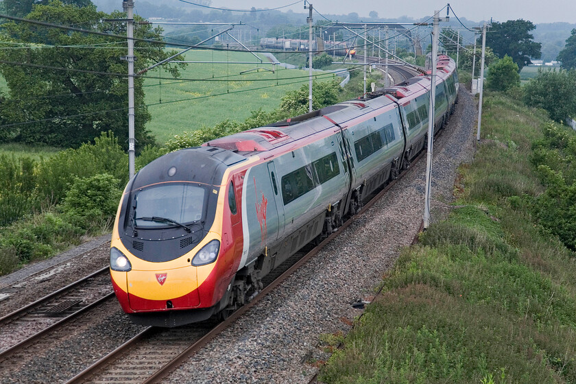 Class 390, VT 05.33 Preston-London Euston, Milton Crossing 
 An unidentified Class 390 passes Milton crossing between Blisworth and Roade working the 05.33 Preston to Euston service. This is a limited stop 'fast' service that has taken less than two hours to reach this point. Another Virgin Pendolino can be seen working north. 
 Keywords: Class 390 05.33 Preston-London Euston Milton Crossing