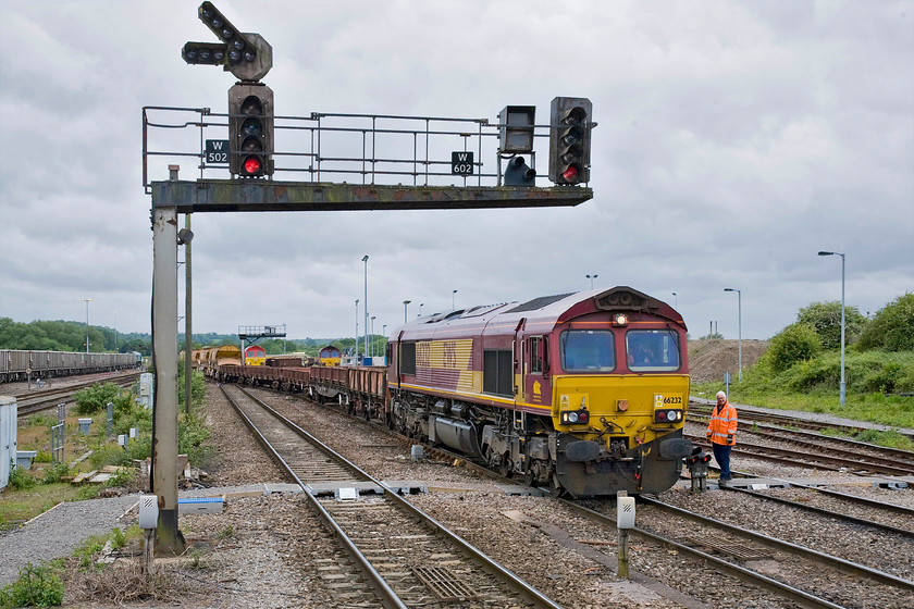 66232, 14.47 Eastleigh East Yard-Westbury engineer s train, Westbury station 
 A busy scene at the western end of Westbury station sees 66232 at the head of the 14.47 from Eastleigh Yard, a varied engineer's train. The train is currently straddling three lines as the crew discuss the moves required to get it into the yard over to the right of the image. Notice the signal gantry that holds W502 and W602. This was installed in 1984 when the superb mechanical signalling and five boxes were swept away following the opening of the Westbury PSB. Ironically, some thirty-five years later the future of the PSB, located to the east of the station, is now in doubt as Network Rail outlines its plans to build a number of regional signalling centres. 
 Keywords: 66232 14.47 Eastleigh East Yard-Westbury engineer's train Westbury station