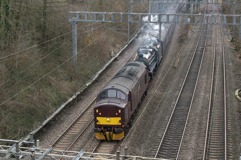 37516 & 44781, 09.44 Southall-Carnforth (5Z21), Hyde Road bridge 
 I selected this spot at Hyde Road bridge in Roade as I thought that this working would only be the two locomotives and a support coach that would have fitted in the frame. However, it was in fact a fairly lengthy set of stock being towed as the 09.44 Southall to Carnforth. Running as 5Z21 it was being hauled by 37516 'Loch Laidon' and Black 5 4-6-0 44781 of which the latter was clearly in steam and adorned with some festive tinsel. 
 Keywords: 37516 44781 09.44 Southall-Carnforth 5Z21 Hyde Road bridge