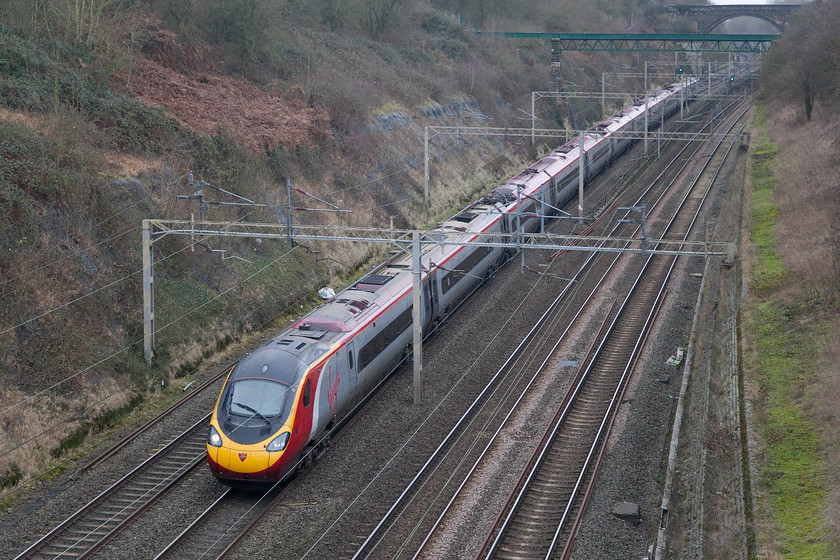 390112, VT 10.47 Liverpool Lime Street-London Euston (1A27), Roade Cutting 
 390114 works the 1A27 10.47 Liverpool Lime Street to Euston express through Roade Cutting. The green structure above the rear of the train is an aqueduct that carries a stream across the cutting. It has recently been repaired by contractors as more water appeared to be leaking out of it into the cutting than was actually being carried across! 
 Keywords: 390112 10.47 Liverpool Lime Street-London Euston 1A27 Roade Cutting