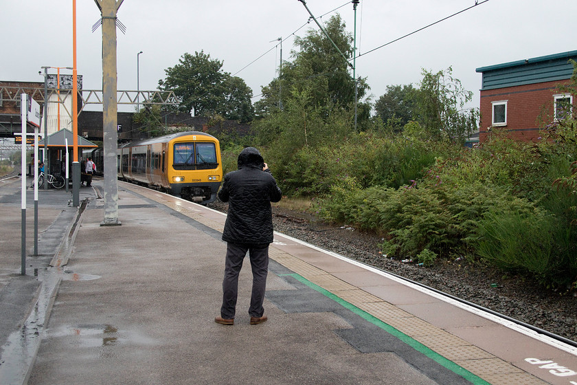 323342, LN 10.16 Four Oaks-Redditch (2R29, 3L), Duddeston station 
 Andy, in his rain-soaked jacket, photographs 323342 arriving at Duddeston station in the centre of Birmingham. It is working the cross-city 10.16 Four Oaks to Redditch service. To the right, the trees mark the spot of the former steam shed and extensive sidings that feature in many contemporary photographs. In their final years, they were used to stable DMUs that were used throughout the West Midlands prior to electrification. 
 Keywords: 323342 10.16 Four Oaks-Redditch 2R29 Duddeston station