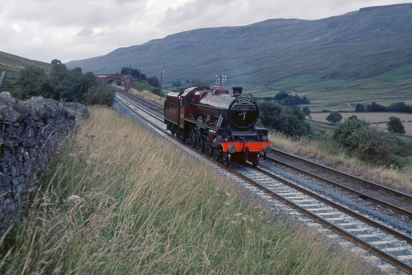 5690, wrong line LE to assist failed freight at Garsdale, Ais Gill SD773979 
 In the pre-internet days getting news when out waiting for trains was all but impossible. It was a case of waiting about for hours in the hope that what you went to see would turn up! This was the case here at Angrholme just south Ais Gill on the fabled Settle and Carlisle route. Graham and I had driven many miles to capture one of BR's Cumbrian Mountain Express charters so decided to stick it out after the train had not turned up an hour after it should have passed. Eventually, we were surprised to hear and then see 5690 'Leander' running light engine and wrong line. A little bemused by this movement we hung about for a little longer and after about forty-five minutes 5690 returned north again running tender first and right line. It transpired that the steam locomotive had been sent south to assist a failed freight hauled by 40179 into a refuge siding at Garsdale station. 
 Keywords: 5690 Leander wrong line LE to assist failed freight at Garsdale, Ais Gill SD773979