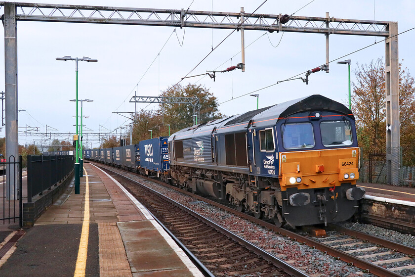 66424, 13.47 DIRFT-Tilbury (4L48, 29L), Wolverton station 
 The daily 4L48 'Tesco Express' passes through Wolverton station with 66424 'Driver Paul Scrivens 1969-2021' leading. I captured this locomotive at DRS's Crewe open day on the day of its naming on a hot day in July 2021, see....https://www.ontheupfast.com/p/21936chg/30029939666/nameplate-66424-display-crewe-gresty 
 Keywords: 66424 13.47 DIRFT-Tilbury 4L48 Wolverton stationDriver Paul Scrivens