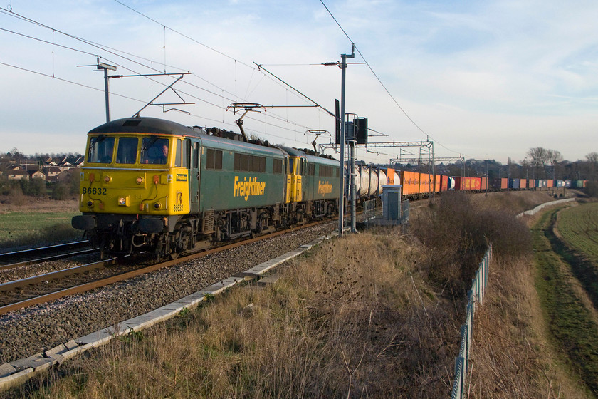 86632 & 86612, 10.10 Tilbury-Crewe Basford Hall (4M54), Wilson`s Crossing 
 I had not prepared myself for the unexpected passing of the 10.10 Tilbury to Basford Hall multimodal working and was thus not in the position to capture the double-headed class 86s properly at Wilson's Crossing north of Northampton. Thus, the electrification masts have interfered with the image with one growing out of the roof of 86632 and the other blocking the rear cab of 86612! In addition, I have not managed to get the rear of the long train in the shot. However, the use of these veteran AC electrics on freight is to be recorded as often as possible as I suspect that it will not continue for a lot longer as availability of spares parts and maintenance of these fifty year old locomotives become more problematic. 
 Keywords: 86632 86612 10.10 Tilbury-Crewe Basford Hall 4M54 Wilson`s Crossing