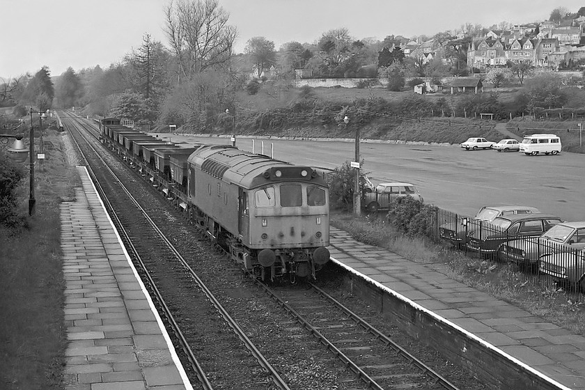 25170, up PW train, Bradford-on-Avon station 
 Just after 'The Sussex Downsman' railtour had passed through Bradford-on-Avon station, the distant colour light BJ102 turned green. To us spotters this meant that there was a non-stoping train heading along the Avon Valley from Bathampton Junction. I waited for a short while and was rewarded with this lovely un-fitted freight composed of ballast wagons probably organised by the PW department headed by 25170. Class 25s were not very common in this area of Wiltshire so it was nice to see. Also take note of the the range of 60s and 70s cars in the station car park that occupies the site of the old goods yard and shed. 
 Keywords: 25170 up PW train Bradford-on-Avon station