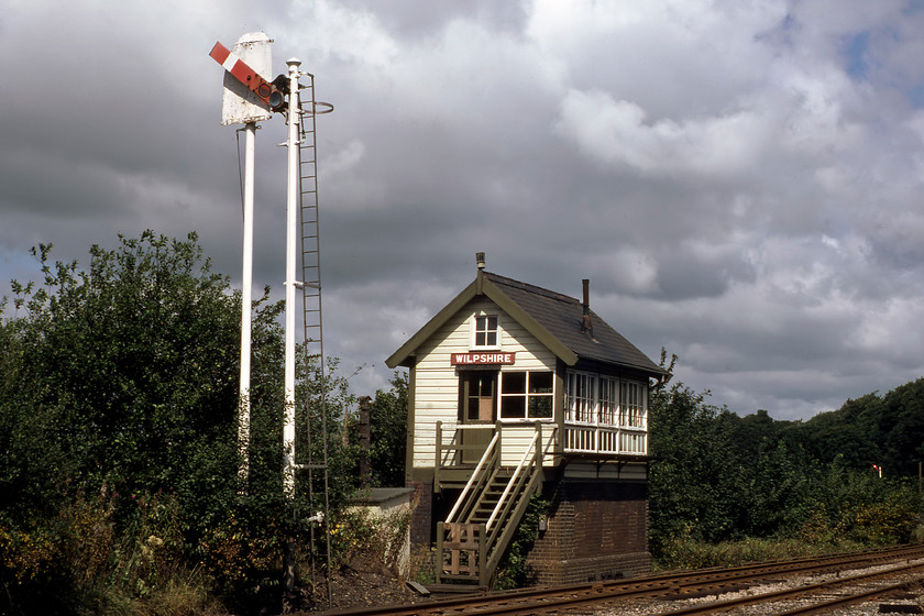 Wilpshire signal box (L&Y, date not known) 
 The superb Wilpshire signal box is seen under threatening skies. It is a Lancashire and Yorkshire structure that I can find precious little about even its date of construction. Located just to the north of Blackburn on the line that joins the Settle and Carlisle route at Hellifiled during the time of our visit it was switched out. The line had been reduced to freight only to serve cement works at Horrocksford and was almost certainly going to close if the S & C went the same way. Happily, the latter was saved and passenger services returned to this route in 1994 as far as Clitheroe. Noice the rather unusual sighting screen behind the home signal standing atop its own post and the height of them both! 
 Keywords: Wilpshire signal box Lancashire and Yorkshire L & Y