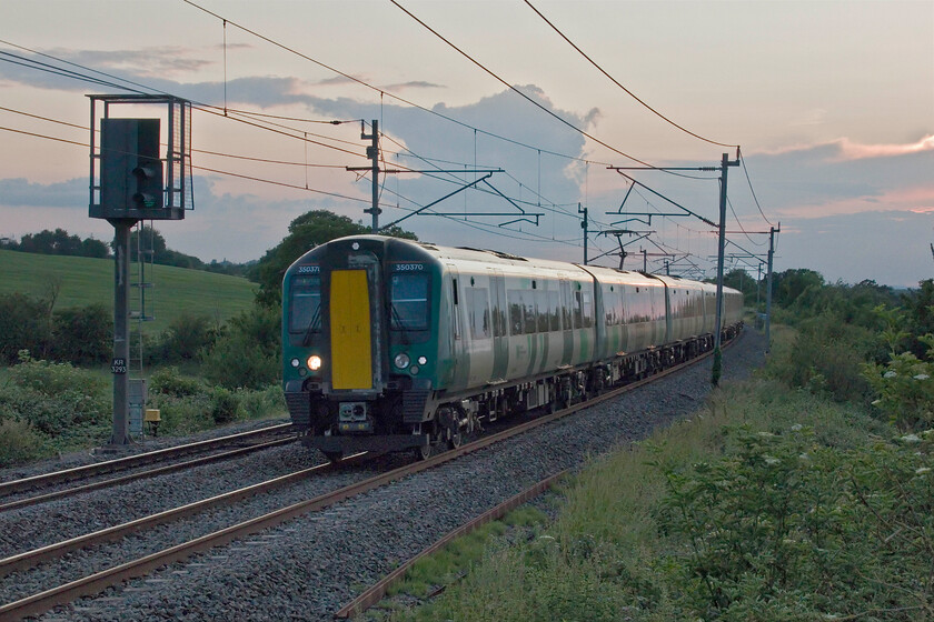 350370 & 350113, LN 19.13 Crewe-London Euston (1U44, 17L), Milton crossing 
 The final photograph of my evening trip out on the longest day as the sun has all but gone shows 350370 and 350113 pass Milton crossing near Blisworth working London Northwestern's 19.13 Crewe to Euston service. This train was also affected by problems in the London area arriving seventeen minutes late after passing me here on time. I love the cloudscape in this view that gives a portent of a possible summer storm but this didn't happen with it melting away overnight and a super day dawning the next morning. 
 Keywords: 350370 350113 19.13 Crewe-London Euston 1U44 Milton crossing London Northwestern Desiro