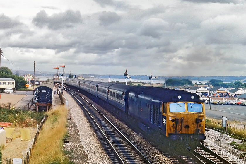 50042, 08.30 London Paddington-Penzance (1B34), Dawlish Warren 
 50042 'Triumph' passes Dawlish Warren station with the 1B34 08.30 London Paddington to Plymouth. Note the signal box at the far end of the station. This has obviously now gone but a modern style replacement has been built as a private residence on the other platform. The ex-GWR camping coaches can be seen to the left, which has always been a notable feature on this piece of land just west of the station. 
 Keywords: 50042 08.30 London Paddington-Penzance 1B34 Dawlish Warren