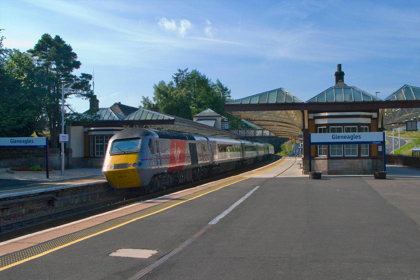 43272, GR 07.55 Inverness-London King`s Cross (1E13), Gleneagles station 
 There is no doubting as to where this picture is taken with its huge running in signs at ninety degrees to where they are usually placed. HST power car 43272 brings up the rear of the 07.55 Inverness to King's Cross 1E13 service as it leaves Gleneagles' impressive station. For such an undefined location and with there being no settlement of that name, Gleneagles station obviously has an interesting history. It was opened as Crieff Junction in 1856 to be renamed by the Caledonian Railway in 1912 and then comprehensively rebuilt in 1919 following the end of World War One. The purpose of the rebuild was that the very grand Gleneagles Hotel had just opened very close by to the north and it was felt that a station of suitable stature should match the opulence of the hotel. Last year (2014) the hotel and golf course hosted The Masters won by Bubba Watson at eight under. In preparation for this event, the station underwent a one million pound improvement package that included a new link road (seen in the far right of the photograph) and car parking. In the past, the hotel has also hosted the G8 meeting of political leaders in 2005 hosted by the then prime minister Tony Blair. 
 Keywords: 43272 07.55 Inverness-London KIng`s Cross 1E13 Gleneagles station East Coast HST Virgin East Coast High Speed Train