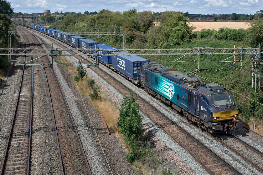 88003, 13.51 DIRFT-Tilbury FLT (4L48, 4L), Victoria bridge 
 88003 would normally be storming past this spot just south of Roade leading the 13.51 DIRFT to Tilbury Tesco Express but today it was pathed behind the much slower running 4L46 that was Class 66 led. 88003 'Genesis' was running on caution for quite some time with the driver probably champing at the bit given the massive power advantage it has over its diesel counterpart! 
 Keywords: 88003 13.51 DIRFT-Tilbury FLT 4L48 Victoria bridge Genesis