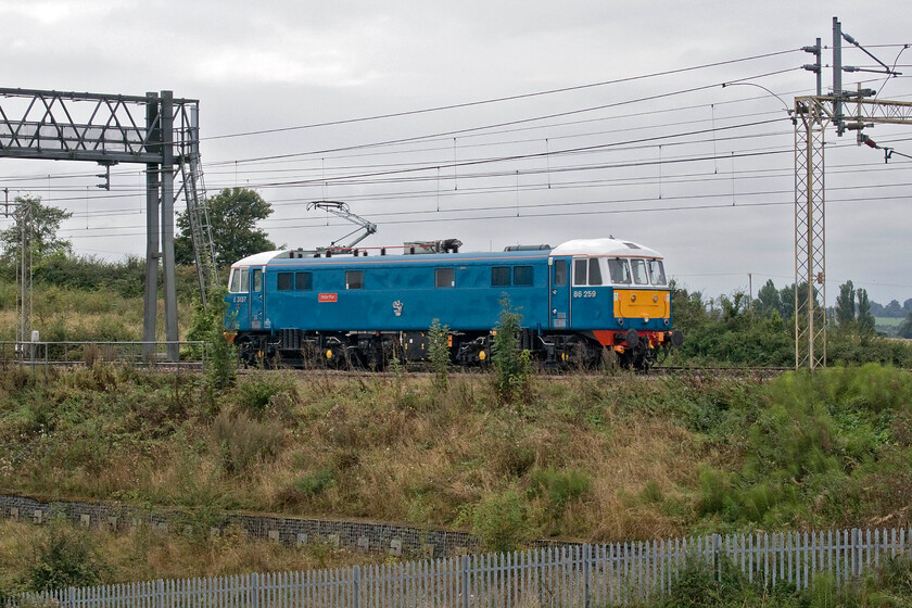 86259, 12.11 Acton Lane Reception Sidings-Rugby CS (0Z88, 43E), between Roade & Ashton 
 Having worked another successful railtour yesterday to Carlisle and back 86259 'Les Ross/Peter Pan' heads light engine back to its weekday base at Rugby. Running very early as 0Z88, the 12.11 Acton Lane Reception Sidings to Rugby Carriage Sidings, it is seen between Roade and Ashton on the down slow line that will take it via Northampton. 
 Keywords: 86259 12.11 Acton Lane Reception Sidings-Rugby CS 0Z88 between Roade & Ashton Les Ross Peter Pan