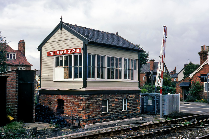 Little Bowden Crossing signal box (LNWR, 1879) 
 Little Bowden Level Crossing signal box is seen in Market Harborough. It was located where the LNWR route from the town to Northampton passed over Scotland Road. The box was a typical LNWR structure dating from 1879. When the line closed the box was saved and is now in use at the Northampton and Lamport Railway being renamed Pitsford and Brampton. When I took this photograph the line had fallen out of frequent use with just the very occasional freight, engineering or diversionary train. Almost a year to the day that I stood on the up track and took this photograph the line was shut by BR. Many now rue the day that this event took place as the lack of strategic lines effectively running west to east linking mainlines is a problem. Just consider now if it was in use and electrified, it would then link the WCML with the MML with the wires now planning to reach Market Harborough by the end of 2022. However, the users of the ever-popular Brampton Valley Way that follows the old trackbed would not be so keen! 
 Keywords: Little Bowden Crossing signal box LNWR railway