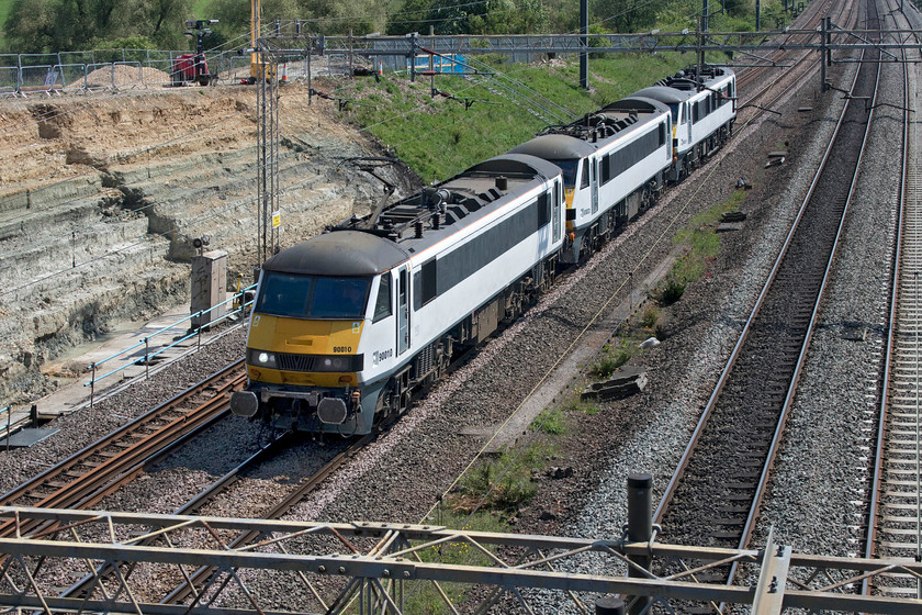 90010, 90003 & 90011, 08.42 Norwich Crown Point-Crewe Basford Hall (0Z25, 22L), Ashton Road bridge 
 The 08.42 Norwich Crown Point to Crewe had been inserted into the timetable all this week but had not run until today! It was there on order for former Greater Anglia Class 90s to move from their former base in Norwich to their new home in Crewe's Basford Hall to work for Freightliner. 90010, 90003 and 90011 'Let's Go East of England' pass the site of embankment stabilisation work at Ashton Road bridge just south of Roade running as 0Z25. All the locomotives look smart and ready for work with 90011 still wearing its nameplates. 
 Keywords: 90010 90003 90011 08.42 Norwich Crown Point-Crewe Basford Hall 0Z25 Ashton Road bridge GA Greater Anglia Freightliner Let's Go East of England