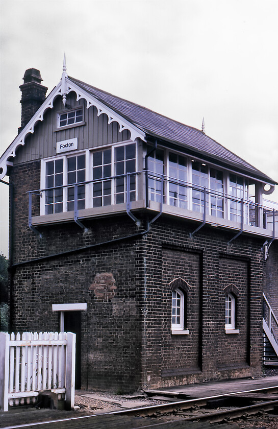 Foxton signal box (GN, 1883) 
 At the time of writing in 2023, Foxton 'signal' box is still open and looks very similar and indeed, much smarter to this 1981 view apart from the usual 'upgrades' in the form of new windows, steps and the removal of the external gallery this probably when the line was electrified. Of particular note is the ornate bargeboarding and tall finials both features of many a Great Northern box. From February 1983 the box was downgraded to a crossing box, a situation that remains the same today. 
 Keywords: Foxton signal box GN Great Northern