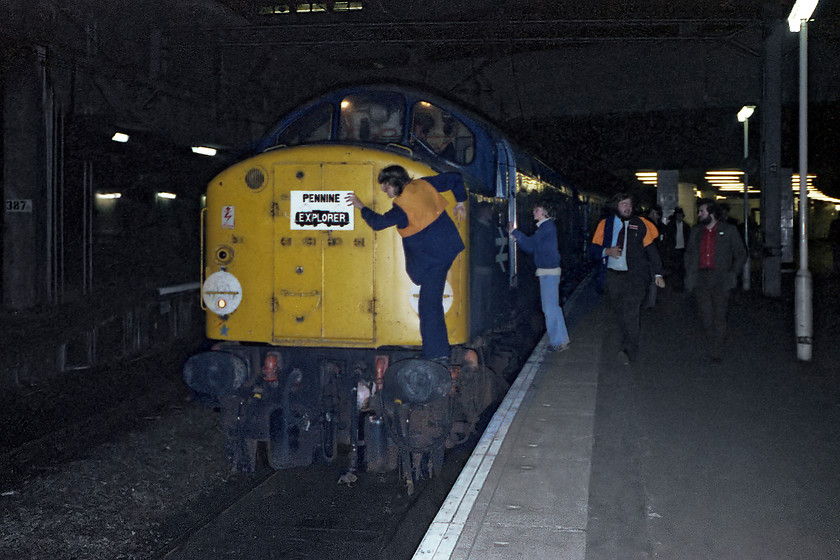 40024, return leg of the Pennine Explorer, Rotherwood Exchange sidings-Cardiff Central, Birmingham New Street station 
 It's all activity on arrival at Birmingham New Street. Whilst some cabbing takes place of 40024, the headboard is removed before the loco. is detached from the stock of the returning Pennine Explorer railtour. All these years on I am surprised at how powerful my little flash was attached to the base of my tiny Rollie B35 camera; it gives a good spread of illumination. The use of a flash is not something that should be encouraged and on today's railways and for obvious reasons, it is banned under the NR guidelines for photographers. 
 Keywords: 40024 Pennine Explorer, Rotherwood Exchange sidings-Cardiff Central Birmingham New Street station