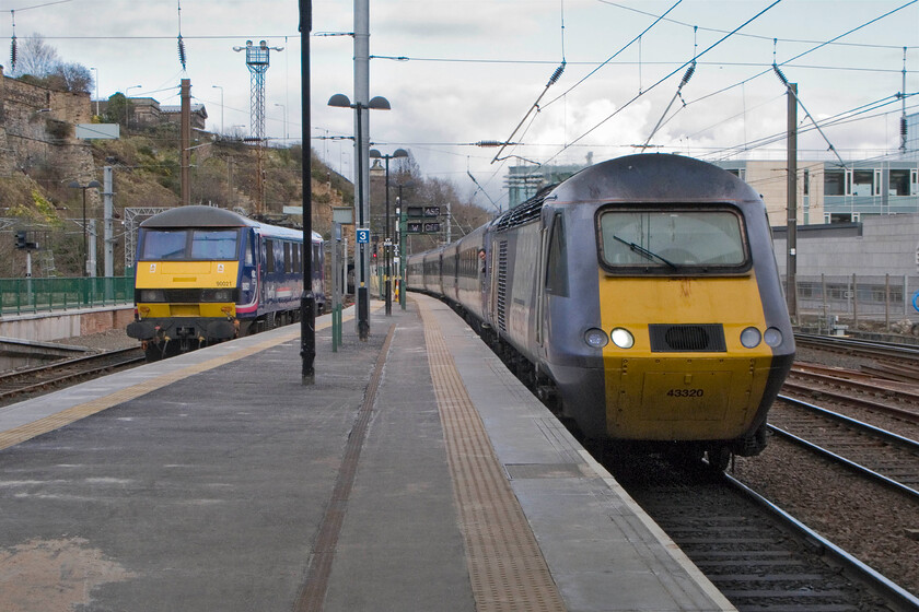 90021, stabled & 43320, GR 12.00 London King's Cross-Inverness, 'The Highland Chieftan', Edinburgh Waverley station 
 East Coast's 12.00 King's Cross to Edinburgh titled train, 'The Highland Chieftain' arrives at Edinburgh Waverley with power car 43320 leading the set. Sitting in the bay platform to the left is the stabled 90021 that will power this evening's southbound Caledonian Sleeper. Above the roof of the HST is not smoke as it appears but in fact an Easter harr drifting in off the North Sea. Later in the afternoon, it would envelop the whole of the city making for a very eerie atmosphere! 
 Keywords: 90021 stabled 43320, GR 12.00 London King's Cross-Inverness The Highland Chieftan Edinburgh Waverley station East Coast HST First Group EWS