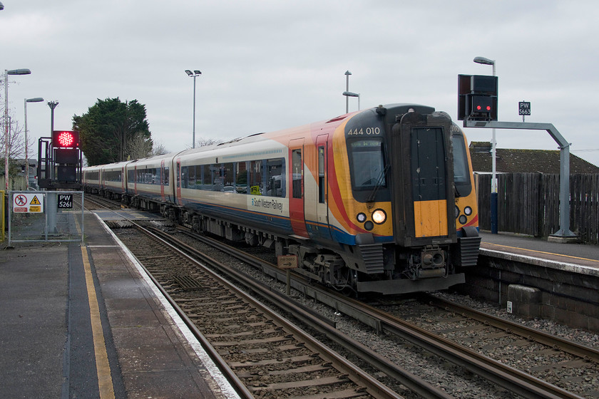 444010, SW 11.20 Weymouth-London Waterloo (1W58, 1L), Wool station 
 444010 crosses the A352 level crossing as it enters Wool station with the 11.20 Weymouth to Waterloo service on an extremely dull day at the start of January. Behind the front of the train there used to be a lovely London and South Western Railway signal box that controlled the level crossing. Now this process is automatic and common sense cannot be permitted to prevail and thus huge congestion can soon build up on the main road. 
 Keywords: 444010 11.20 Weymouth-London Waterloo 1W58 Wool station South Western Railway SWR