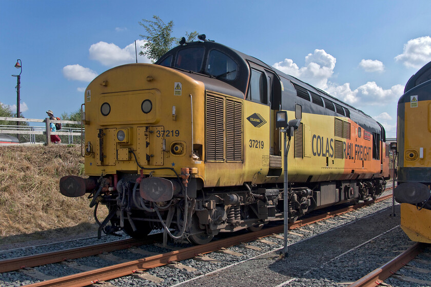 37219 & 37901, on display, Barrow Hill 
 Colas' 37219 'Jonty Jarvis 8-12-1998 to 18-3-2005' looks a little tatty and work stained as it sits on display at Barrow Hill. It sits next to Pheonix's 37901 that by contrast was very shiny and well presented! Whilst DRS has said that it wishes to dispose of its older heritage fleet putting them all up for sale in the summer of 2022 others are continuing to make use of them with the 37s, in particular, remaining extremely versatile locomotives despite their advancing years. Notice the bracketry fitted to the nose of 37219 that supports the Rila track recording equipment. 
 Keywords: 37219 37901 on display Barrow Hil Jonty Jarvis 8-12-1998 to 18-3-2005