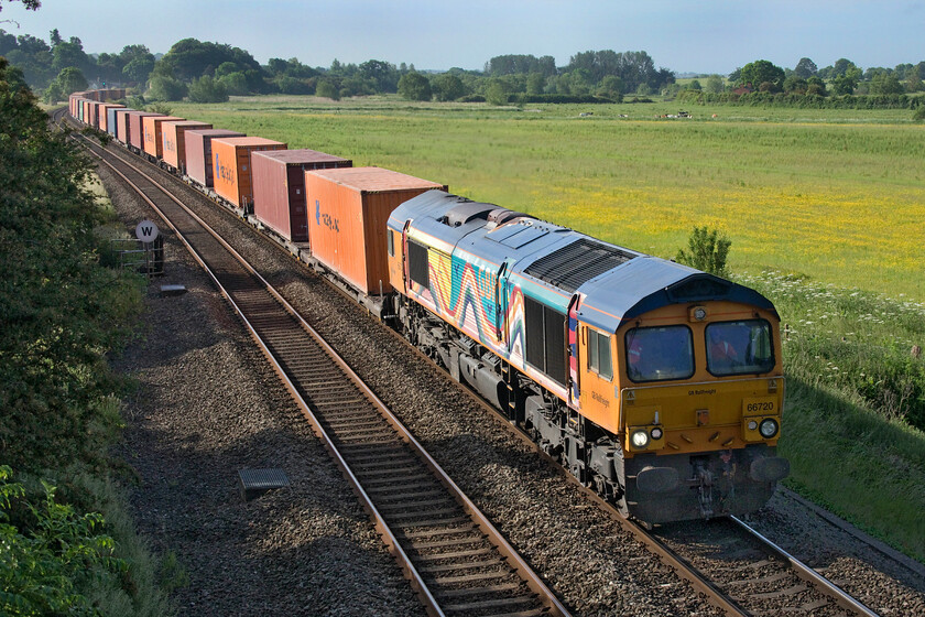 66720, 05.48 Southampton Western Docks-Doncaster iport (4E34, 4L), King's Sutton 
 66720 leads the 05.48 Southampton Docks to Doncaster iport service past King's Sutton in some lovely early morning sunshine that is a little backlit even by this time in the morning just gone 8 am. The GBRf Class 66 certainly strikes quite a pose wearing its one-off special livery with a rainbow and bright paintings on the bodyside with a different nocturnal design on the other side. The vinyls were applied back in 2011 following a competition that was won by a then six-year-old Emily Goodman who was the daughter of a trainee GBRf driver at March. 
 Keywords: 66720 05.48 Southampton Western docks-Doncaster iport 4E34 King's Sutton GBRf